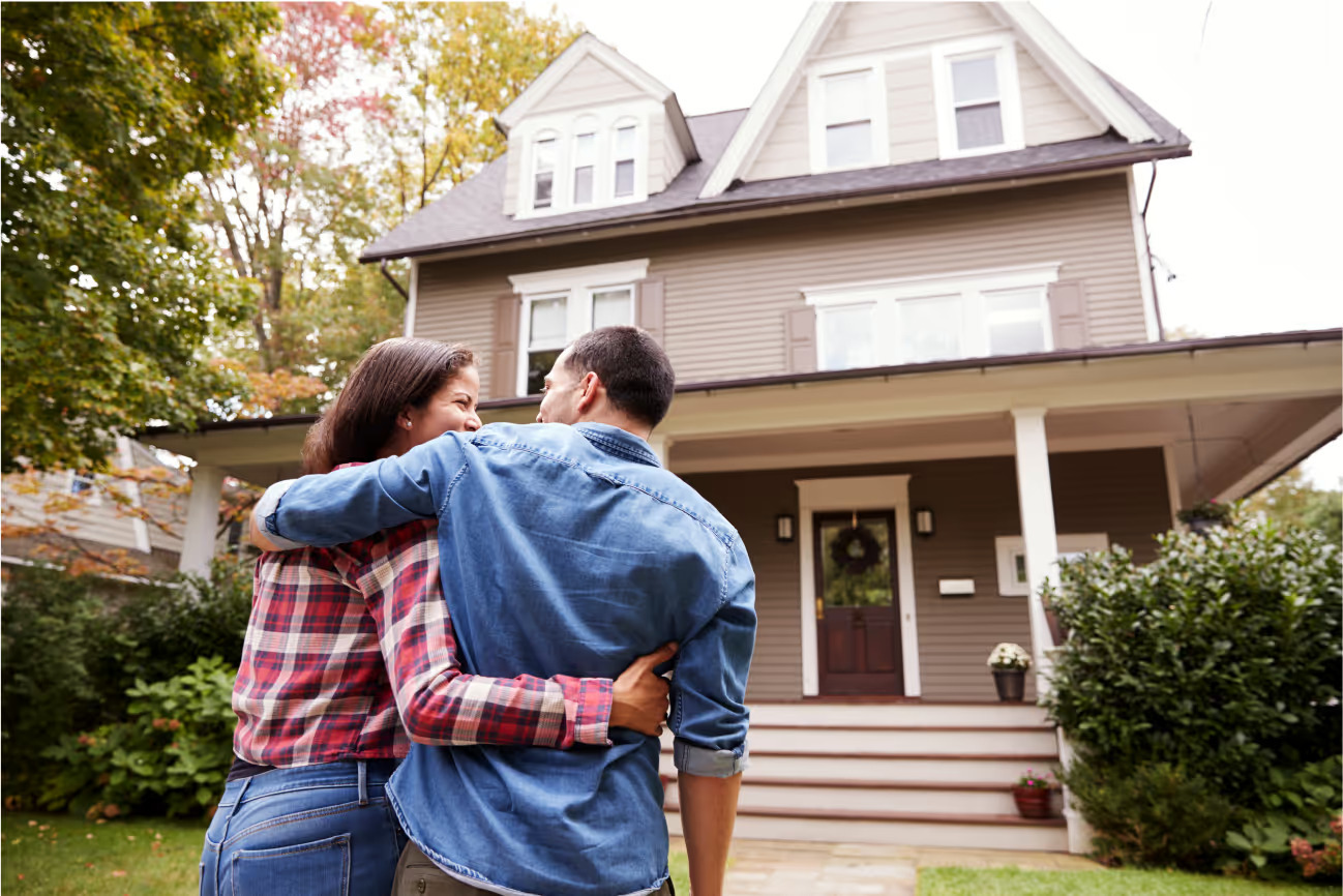 Two people hold each other and walk toward a home.