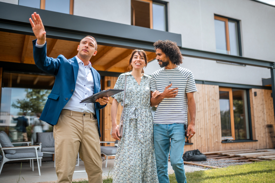 A person with a clipboard shows two people a house